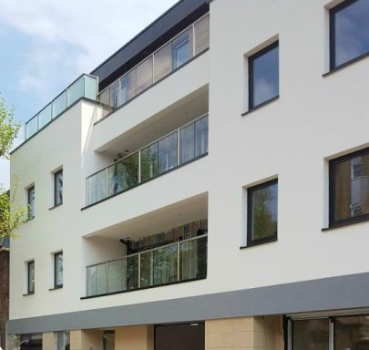 E.W.i Thin Coat Modern three-storey building with balconies and large windows, set against a clear sky.